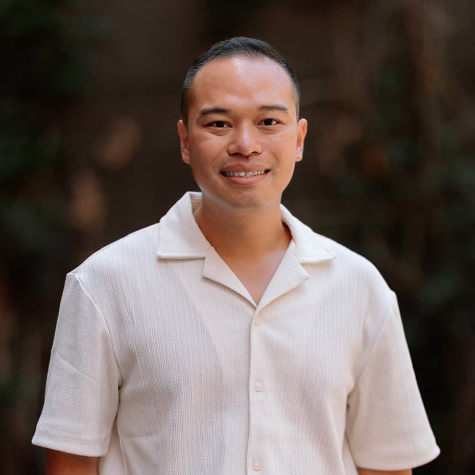 Our Team 4 Smiling man wearing a cream textured shirt, short dark hair and braces.