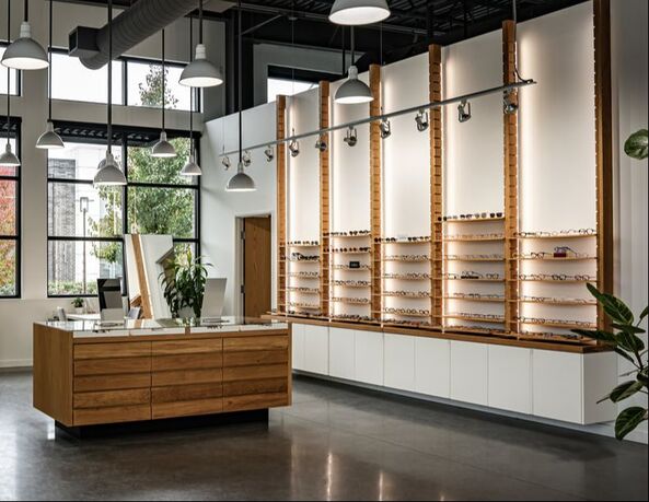 Clean, bright optical store with extensive wooden displays of glasses and a central counter.