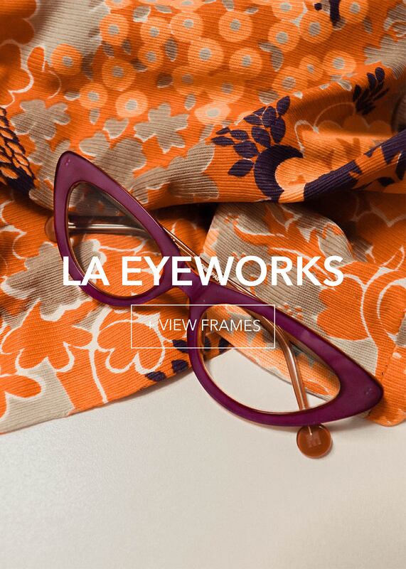 laeyeworks-final1_3 Purple cat-eye glasses lie on vibrant orange fabric with gray and navy floral patterns.