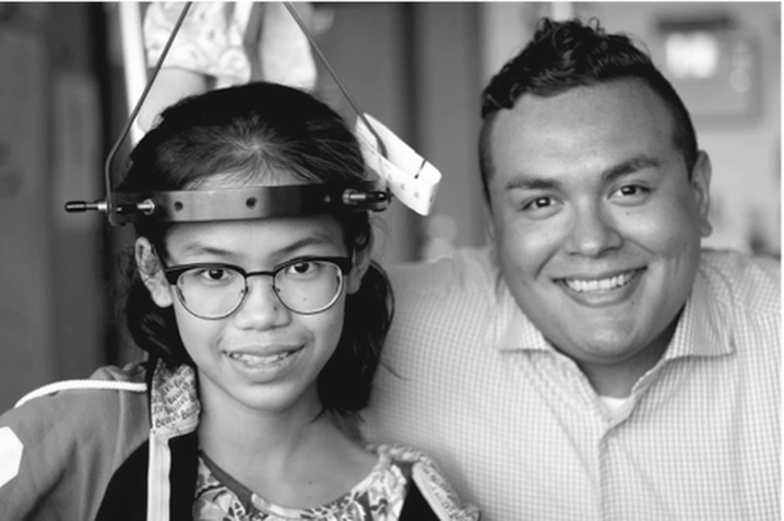 Black and white portrait of a smiling girl with halo traction and a smiling man.