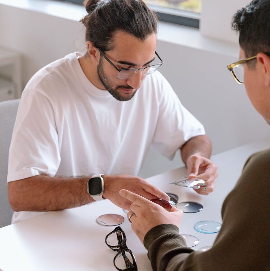 An optician showing a male patient different prescription lens options and tints during a personalized eyewear consultation.